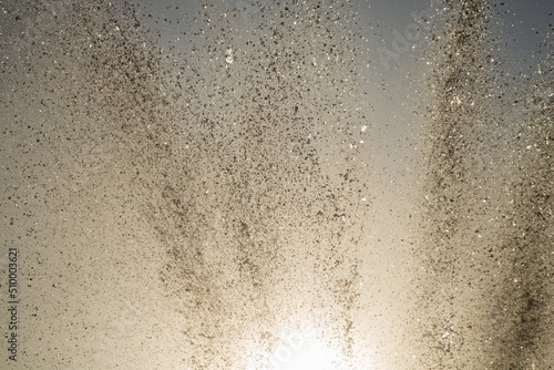 Bright splashes of the water fountain against the blue sky. Abstract color composition in sunshine backlight.