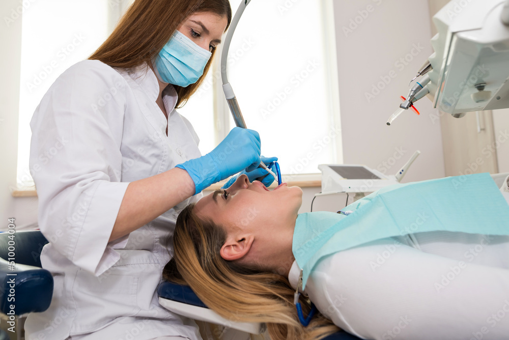 Dentist-hygienist conducts a teeth cleaning procedure for a girl in a dental clinic. Removal of tartar. Dentist-hygienist conducts a teeth cleaning procedure for a girl in a dental clinic. Removal of tartar.