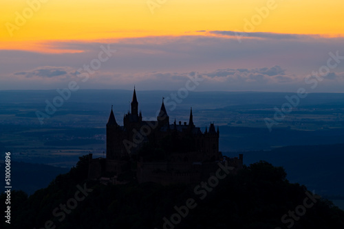 Historic castle silhouette on a hill in Germany near Hechingen south of Stuttgart at evening blue hour. Colorful twilight panorama with iconic monument seen from Zellerhorn viewpoint.