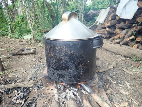 the stove on the wood fire. Dandang is a large pot that is often used for cooking rice (steaming half cooked rice or rice aron). photo