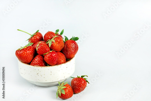 Fresh ripe tasty strawberries in a white bowl on a light background