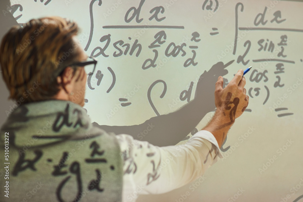 Rear view of university teacher standing in front of projection screen and explaining formula Rear view of university teacher standing in front of projection screen and explaining formula