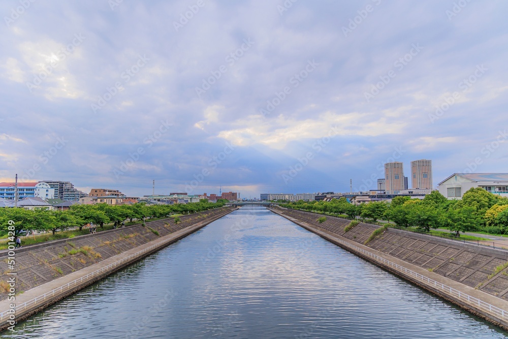 千葉県浦安市境川の橋の上から眺める空と雲の隙間から射す陽光