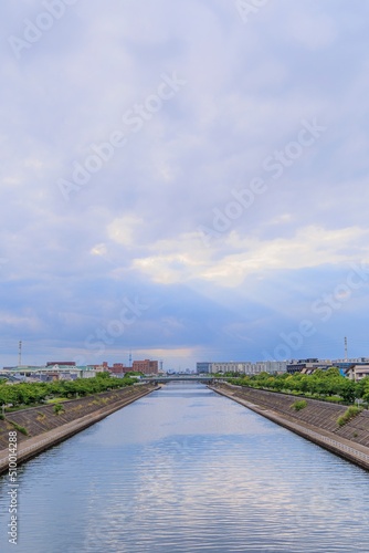 千葉県浦安市境川の橋の上から眺める空と雲の隙間から射す陽光