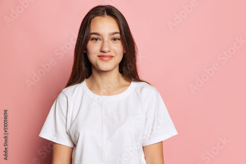 Half-length portrait of young pretty girl in white t-shirt isolated on pink background. Concept of beauty, art, fashion, youth and emotions