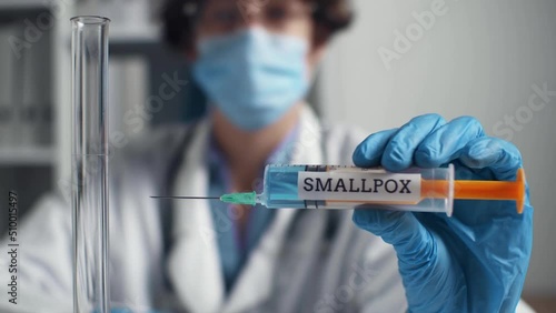 Syringe smallpox vaccine syringe doctor's blurred face. Mandatory vaccination during dangerous epidemic of influenza smallpox. Doctor holds syringe with vaccine. A new virus is spreading in a pandemic photo