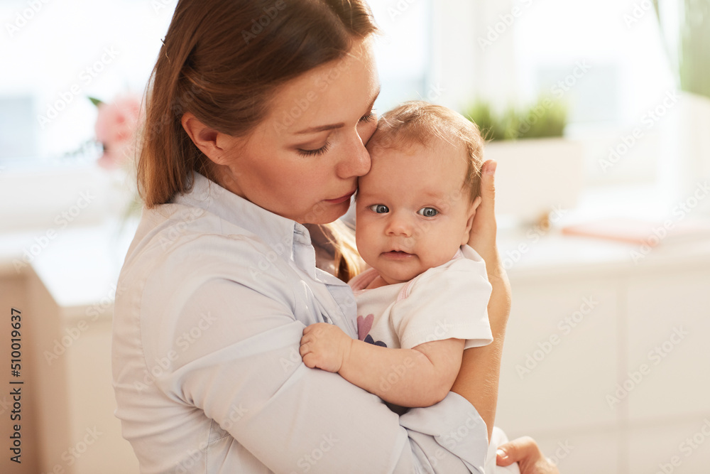 Beautiful young Caucasian woman hugging baby girl with tender and love Beautiful young Caucasian woman hugging baby girl with tender and love