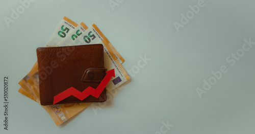 Wallet over the euros and the red arrow. Financial background. Concept of investment  rising cost of living and inflation.
