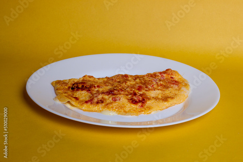 Omelete ovo frito em um prato branco com fundo amarelo isolado