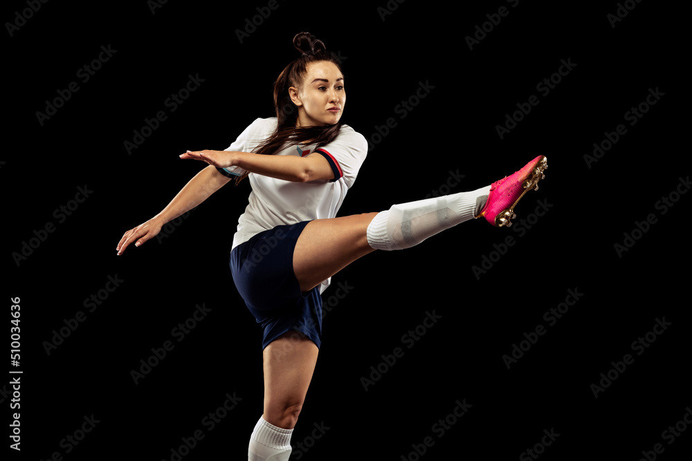 One caucasian energetic woman, soccer, football player in motion isolated on dark background. Sport, action, competitions, games and fitness concept