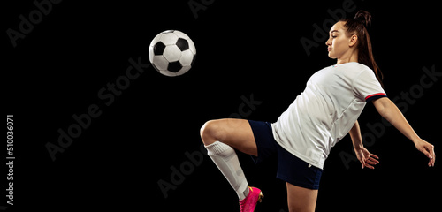 Fototapeta Naklejka Na Ścianę i Meble -  Young caucasian sportive woman, female soccer, football player in motion isolated on dark background. Sport, action, competitions, games and fitness concept