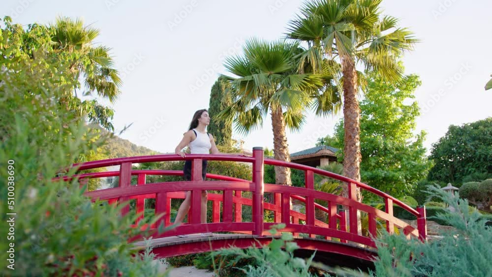 Wide shot of a young woman walking over a bridge and stopping to look around Wide shot of a young woman walking over a bridge and stopping to look around