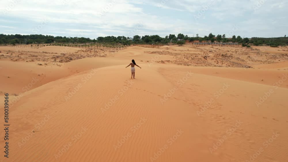 excited woman raising arms on top of desert sand dunes in Mui Ne Vietnam, aerial excited woman raising arms on top of desert sand dunes in Mui Ne Vietnam, aerial