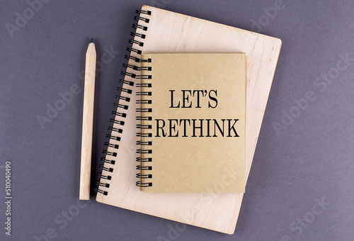 Word LET S RETHINK on notebook with pencil on the grey background photo