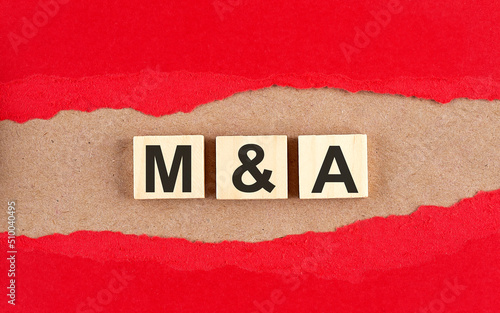 M and A word on wooden cubes on red torn paper , financial concept background