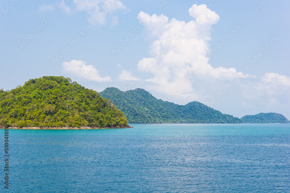 An island in the beautiful tropical sea, blue sky, and green sea.