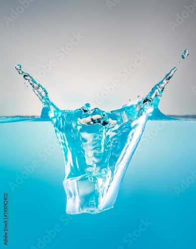 object falling into blue water until splashing on a gray background, freshness, nature, blurry objects