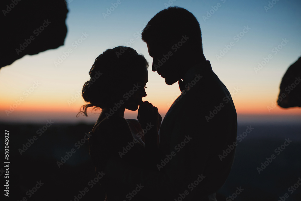 Moonlight highlights the silhouettes of the bride and groom in the mountains