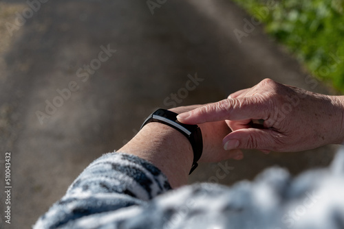 Hands of senior woman check time, sms or pulse using smartwatch app outdoors. Concept of modern technologies and healthy lifestyle.