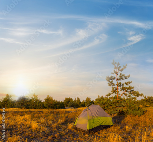 closeup small touristic tent stay among prairie at the sunset, natural travel background