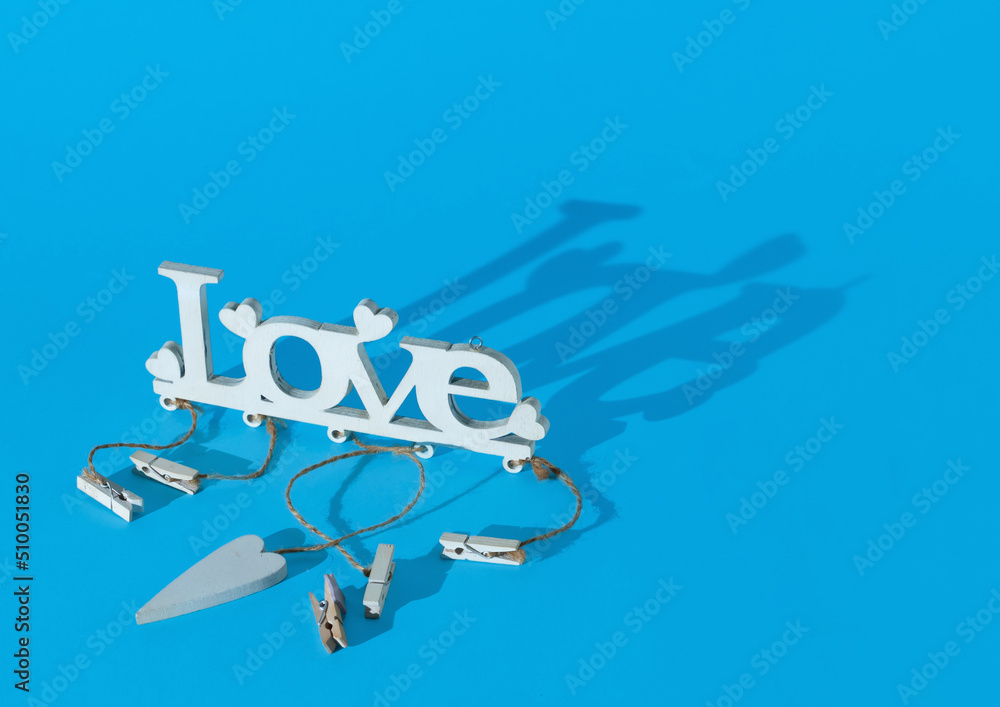 Wooden word LOVE on pastel cyan background with fancy shaddow
