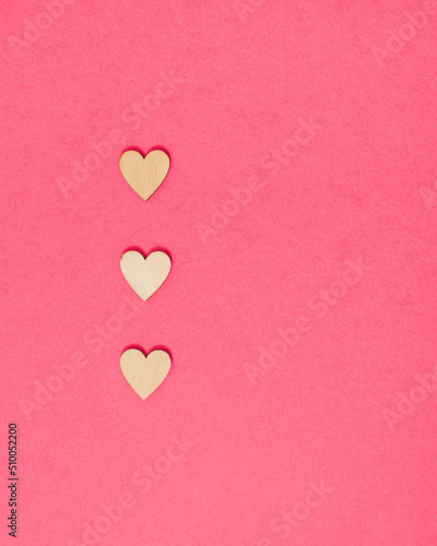 Three hearts laid out on vibrant pink colored background. Minimal love concept with copy space for message. Bright rose romance idea.