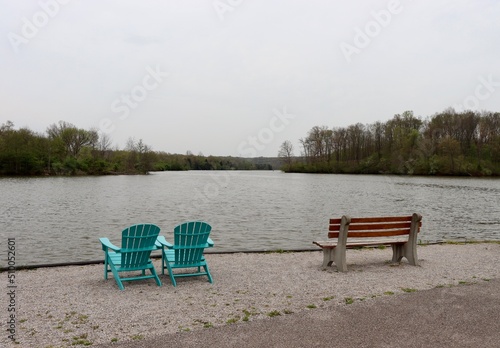 The bench and chairs at the lake on a cloudy day.