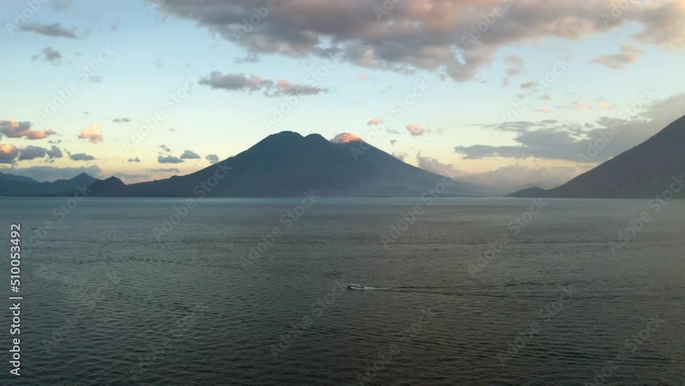 Aerial drone shot of a motor boat going through the Lake Atitlan in Guatemala with the view of mountain range in the background at sunset Aerial drone shot of a motor boat going through the Lake Atitlan in Guatemala with the view of mountain range in the background at sunset
