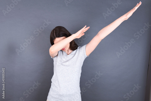 Photo of funky young beautiful Caucasian woman wearing white T-shirt over grey wall show disco move dab photo