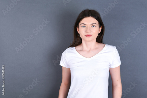 young beautiful Caucasian woman wearing white T-shirt over grey wall feeling confident. 