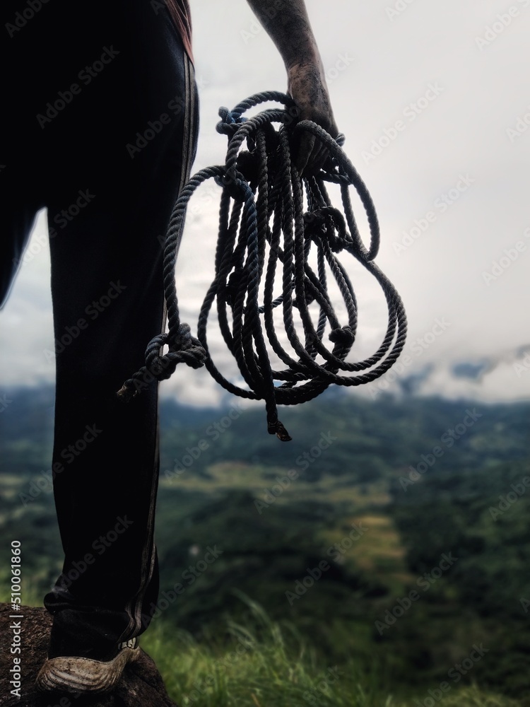 Naklejka premium Hiker ready to climb the mountain with a rope