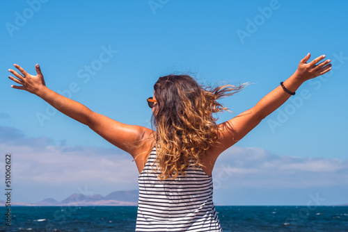 Free curly-haired woman with arms raised