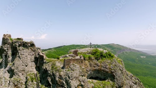 Kojori Fortress near Kojori, Georgia. Tourists visit landmark, look on beautiful valley with sunbeams. Christian cross on the hill near Kojori Fortress. photo