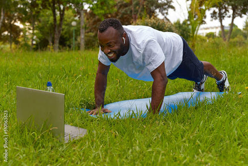 Happy young adult man in the park having online training. Healthy lifestyle.