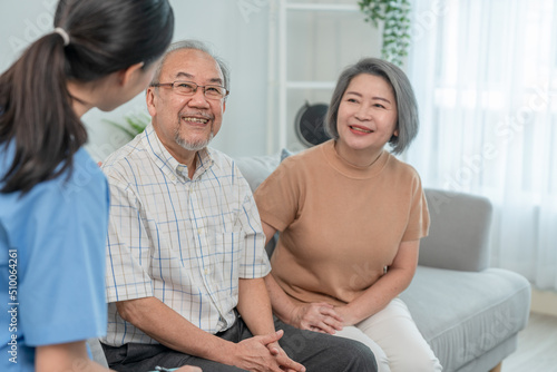 Asian elderly smiling sitting on sofa while young woman caregiver doctor give consultation about health in living room during home visit