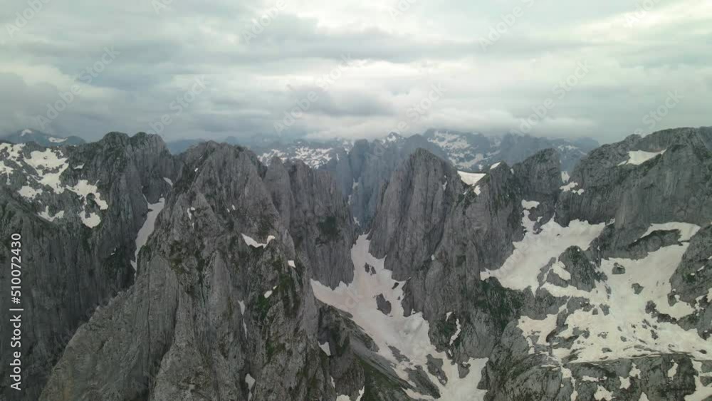 Drone flying backwards over Karanfil mountain group, Albania revealing valley covered in snow Drone flying backwards over Karanfil mountain group, Albania revealing valley covered in snow