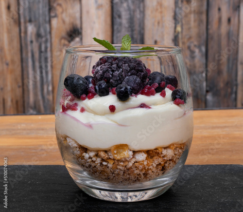 Nutrition. Closeup view of a trifle cup with yoghurt, white chocolate cream, cereal and red berries. 