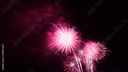 Stunning fuchsia pink fireworks exploding into the city night sky