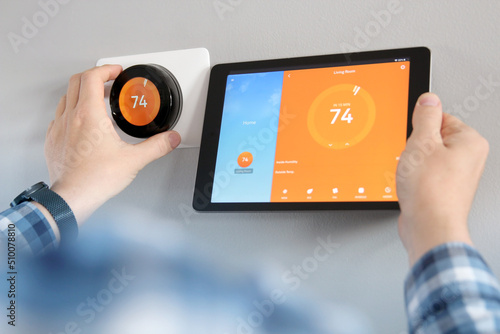 Man is Adjusting a  temperature using a tablet with smart home app in modern living room photo