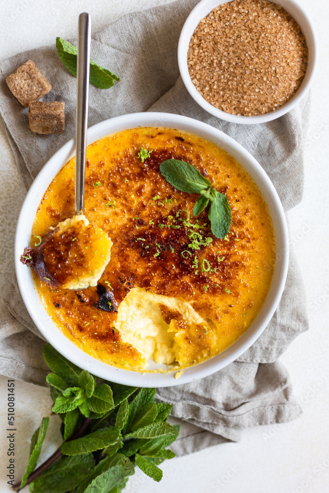 Creme brulee with caramel crust and mint in ceramic dishes. Famous french dessert. Delicious desserts for cafe or restaurant. Top view. Creme brulee with caramel crust and mint in ceramic dishes. Famous french dessert. Delicious desserts for cafe or restaurant. Top view.