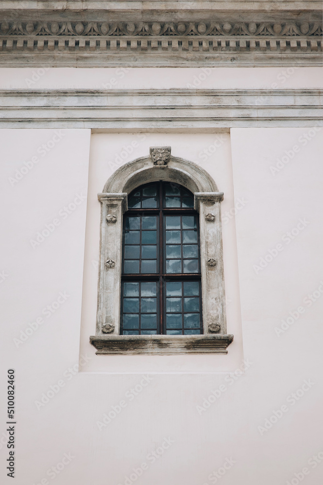 Antique old window with black iron bars framed on a grey wall. The Jesuit Church in Lviv.