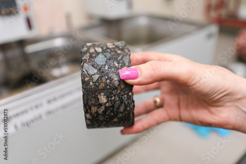 Modern laboratory for testing road samples and materials concept. A sample of the top layer of the road surface in a woman's hand.