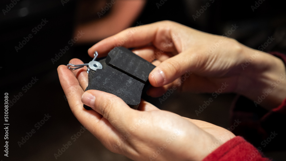 Fototapeta premium Hand holding new car brake pads. Replacing car brake pads. Change the old to new brake disc on car in a garage. Auto repair concept.