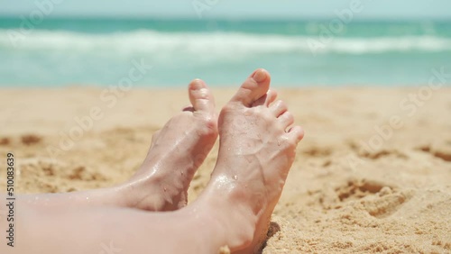 Female foot with hallux valgus close up on the beach on vacation summer day. Woman with foot deformation halluxvalgus enjoy summer sandy beach.  photo