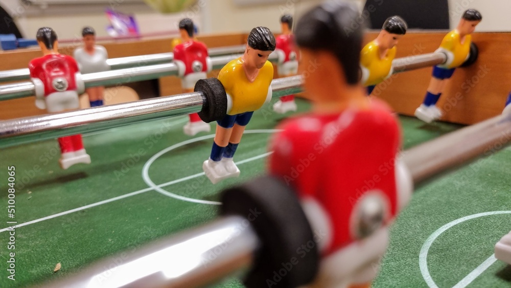 Fototapeta premium Players in a small table foosball game playing in Red and Yellow.