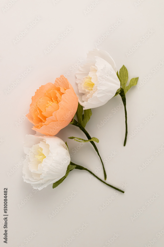 Hand made crepe paper peonies on white background flat lay vertical. Paper peony DIY concept Hand made crepe paper peonies on white background flat lay vertical. Paper peony DIY concept