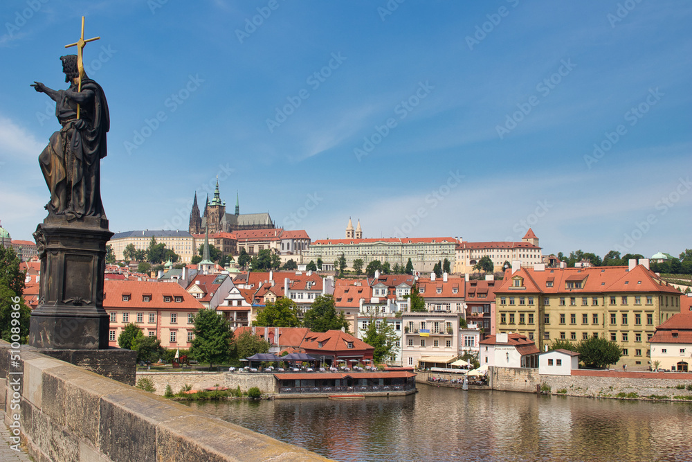 Charles bridge with statue of John the Baptist, Vltava river, Pague castle in a background.