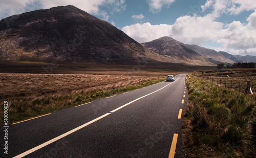 Obraz na płótnie Dramatic landscape scenery with car driving on empty scenic road trough mountains and nature at Connemara National park in county Galway, Ireland w salonie