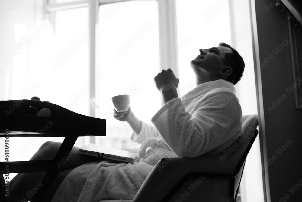 in the photo, a smug man in a bathrobe in hotels lying down enjoying the view from the window