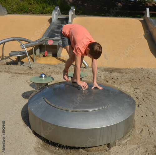 Kind spielt im Sommer auf dem Wasserspielplatz photo